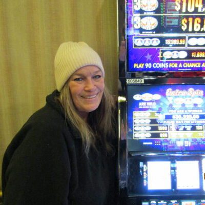 Person smiling beside a slot machine.